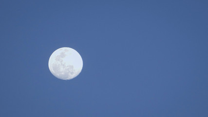 Full moon from afar in the evening, blue background