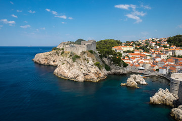 Fototapeta na wymiar Old Town houses with red tiled roofs and rocky green idyllic island in background, Dubrovnik, Dalmatia, Croatia