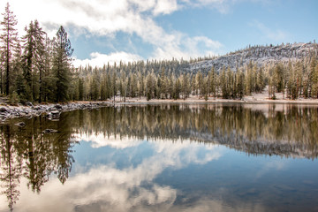 Lake reflecting snow, sky, and forest