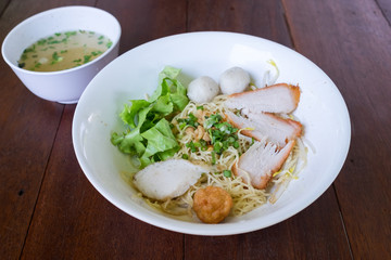 Thai Noodles "Kuay Tiew " with pork and fish meat ball and vegetables with soup on wooden table