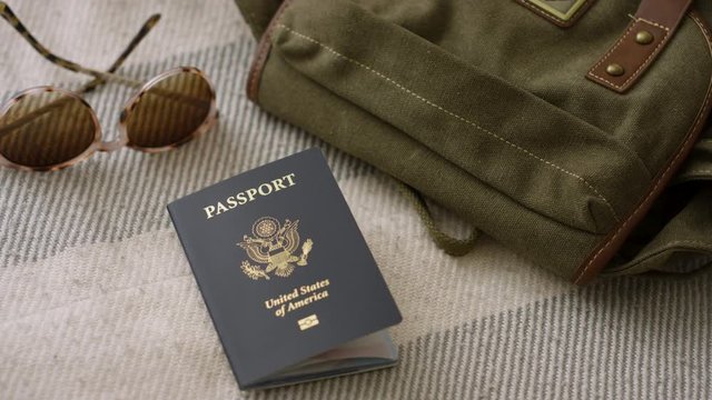 Woman traveler puts United States passport into luggage and grabs sunglasses close up shot