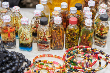 Close-up view of colorful plastic arm rings and glass bottles filled with spiritual content for sale by indigenous aeta vendors in the Philippines