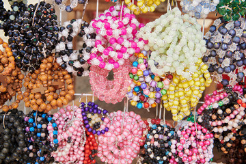 Close-up view of a display of colorful plastic and wood bead rosary bracelets for sale by a vendor during the Ati-atihan Festival in the Philippines