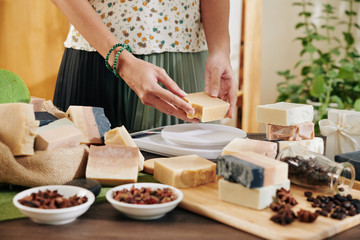 Woman cutting handmade soap in pieces and packing it for customers