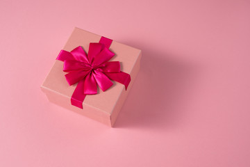Valentine's Day celebration concept. A nice gift from a loved one. Box with a bow on a delicate pink background. Copy space. Flat lay. Close-up.