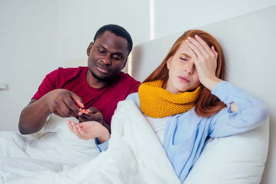 Sick Together. Young Latin Hispanic Man And Redhaired Ginger Woman Sneezing Into Paper Napkins In Bed