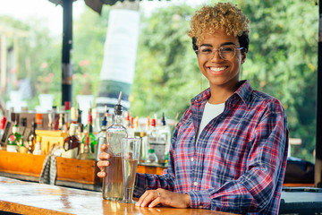 brazilian hispanic mixed race woman barman making beverage alcoholic drink at beach shack in tropic