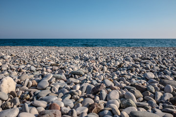 Obraz premium beach with sea pebbles close up on blue sky background. The concept: joy, happiness, positivity, relax, vacation, tourism.