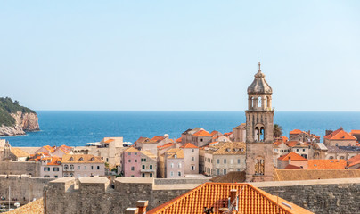 Fototapeta na wymiar Old Town houses with red tiled roofs and rocky green idyllic island in background, Dubrovnik, Dalmatia, Croatia