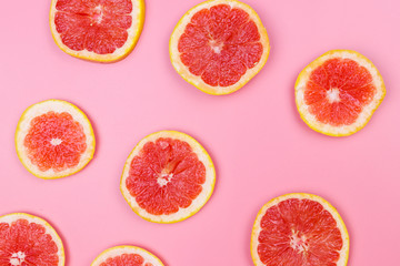 Fototapeta na wymiar Slices of grapefruit on a pink background