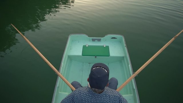 Man sitting in rowing boat on calm lake, top view, Suwalszczyzna, Poland