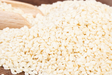 Heap of sesame seeds with wooden scoop