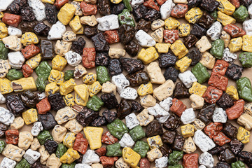 A solid background of small chocolate candies in the shape of co