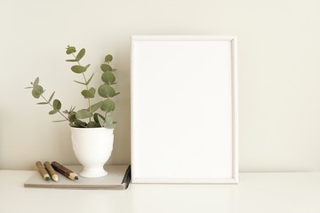 Minimal natural interior, white empty frame mock up, eucalyptus branches, wooden pencils.