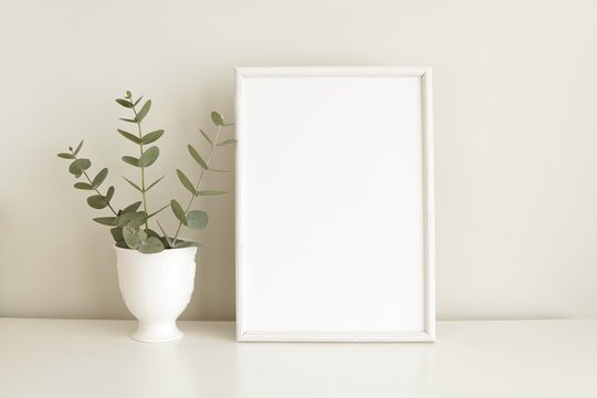 White blank frame mock up, poster, print mockup, simple minimal interior with eucalyptus branch.