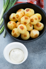 Close-up of roasted potato balls with dipping sauce and green onion, vertical shot, selective focus