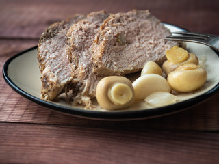 Sliced pork and pickled mushrooms on a ceramic plate. Close-up shot