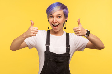 Like! Portrait of optimistic happy hipster woman with violet dyed short hair in denim overalls...