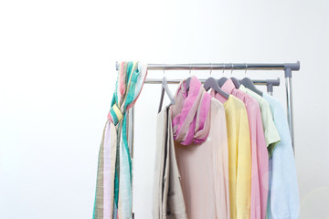 Spring fashion - pastel colored clothes on rail. Female colorful bright spring clothing set of on the racks on white background. Sale at clothing store concept.