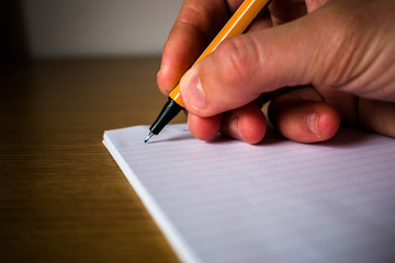 Woman hand holding yellow pencil on notebook closeup view