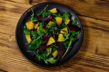 Tasty salad of fresh arugula, beetroot and oranges on wooden table. Top view. Healthy food or vegetarian concept