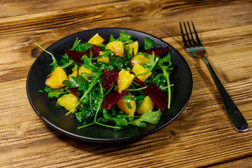 Tasty salad of fresh arugula, beetroot and oranges on wooden table. Healthy food or vegetarian concept