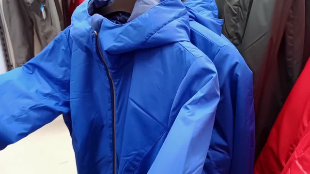 woman looking at a blue jacket in a store