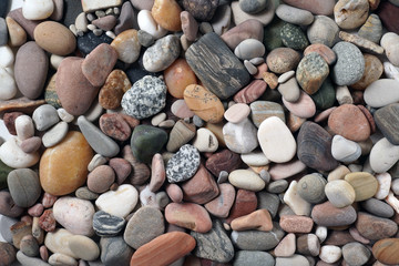 Gravel pattern of colored stones. Abstract nature pebbles background.Small sea stones on the beach, vacation at sea. Top view      