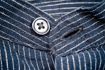 The texture of a denim shirt in dark blue with a small strip on the buttons. Background for fabric and clothes. Fashion, style and practicality.