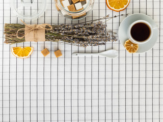 Tea, lavender, sugar and lemon slices on a white checkered tablecloth. Space for text