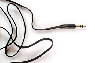 3.5 mm plug with a black wire, shot large on a white background. Background for music and computer equipment.
