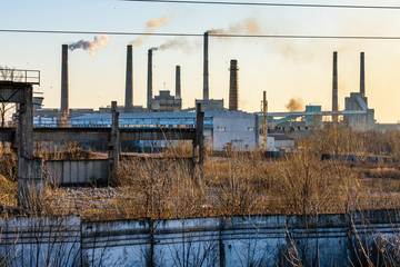 View on smoke pipes of the factory at sunset