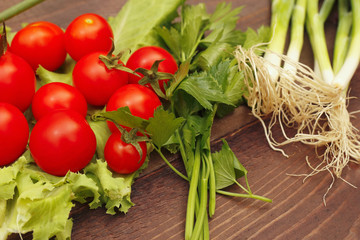 Summer tomatoes and greens on a rustic wooden table