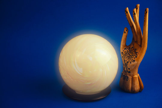 creative esoteric still life with a ball of predictions and wooden female hand on a vibrant blue background