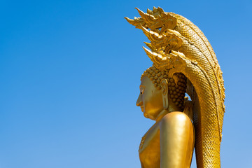 Big Thai Style Buddha Statue with Naga over blue sky. Wat Phra That Suthon Mongkhon Khiri,  Phrae Province, Thailand