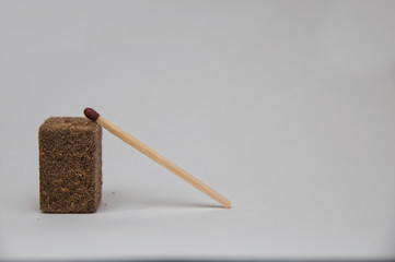 Matchstick leaning into kindling close up with white background