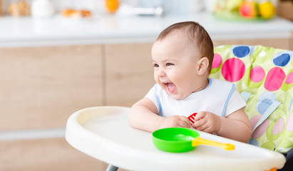 Cute baby playing with toy pan and kitchen spatula