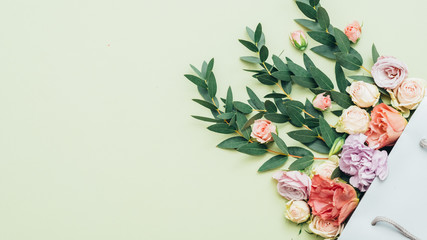 Bouquet delivery. Women day greeting. Multicolor roses green filler flowers in shopping bag.
