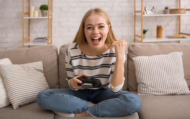 Emotional young woman playing video games at home