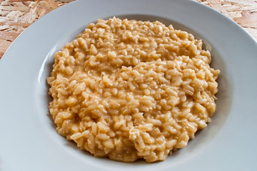 Rice with eggs and parmigiano reggiano on wooden table. Italian risotto with eggs and cheese