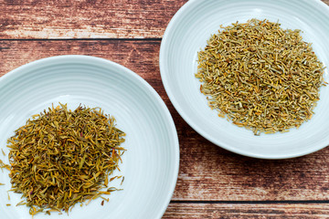 Thyme and rosemary in ceramic jars on wooden background 