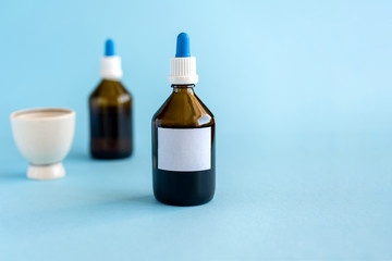 Homeopathic drops and two glass bottles on a blue background. Herbal medicine alternative homeopathy, healthcare concept and pills. copyspace for text