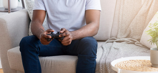 African guy playing video games with joystick at home