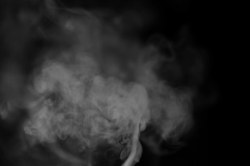 White smoke on a black background. Texture of smoke. Clubs of white smoke on a dark background for an overlay
