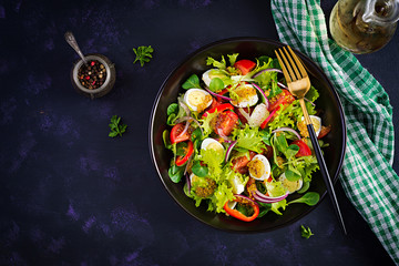 Fresh salad with vegetables tomatoes, red onions, lettuce and quail eggs. Healthy food and diet concept. Vegetarian food. Top view, overhead