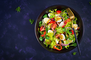 Fresh salad with vegetables tomatoes, red onions, lettuce and quail eggs. Healthy food and diet concept. Vegetarian food. Top view, overhead