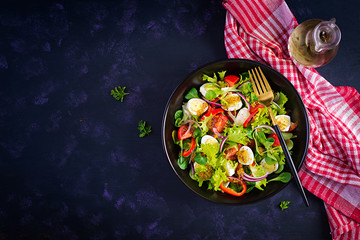 Fresh salad with vegetables tomatoes, red onions, lettuce and quail eggs. Healthy food and diet concept. Vegetarian food. Top view, overhead