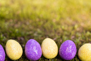 oeufs de pâques jaune et violet avec des paillettes sur un fond vert