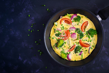 Omelette with broccoli,  tomatoes and red onions in iron skillet. Italian frittata with vegetables. Top view, overhead