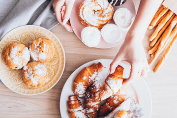 Homemade pastry. Bakery food assortment. Female hand taking croissant. Served muffins meringue.